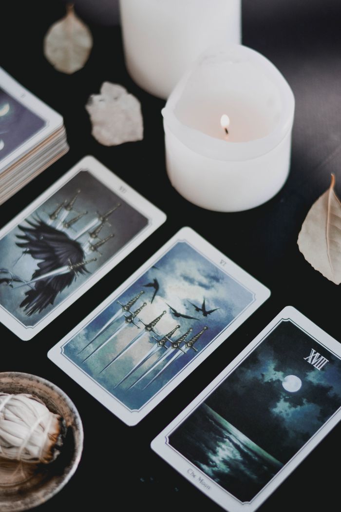 About A close-up of mystical tarot cards and candles on a black surface, perfect for spiritual themes.