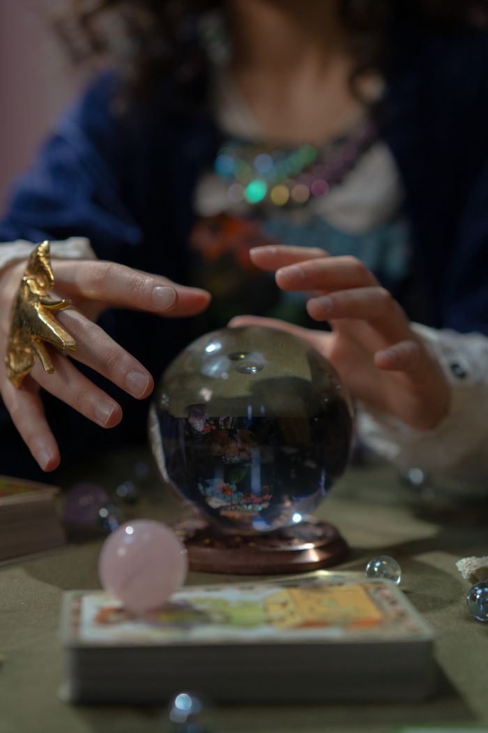 A captivating fortune teller engaging in divination with a crystal ball and tarot cards, symbolizing mysticism.