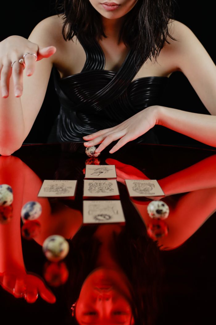 Woman performing a tarot reading on a reflective glass table, creating a mystical ambiance.